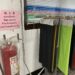 A fire extinguisher mounted on a wall next to multilingual safety instructions and a rack of colorful fabric samples.